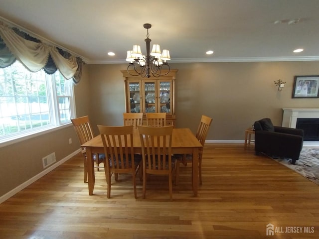 18 Timber Rd, East Brunswick, NJ 08816 - dining space featuring a chandelier, baseboards, light wood-style floors, a fireplace, and crown molding