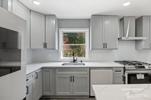 kitchen featuring sink, wall chimney range hood, appliances with stainless steel finishes, and gray cabinets