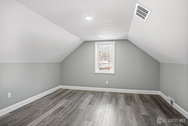 additional living space with vaulted ceiling and dark hardwood / wood-style floors