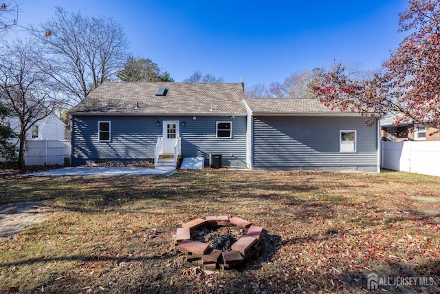 rear view of property featuring a lawn, an outdoor fire pit, central air condition unit, and a patio area