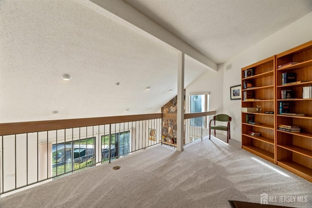 interior space featuring carpet flooring, vaulted ceiling with beams, and a textured ceiling