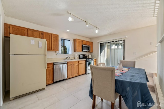 kitchen featuring sink, light tile patterned floors, a textured ceiling, and appliances with stainless steel finishes