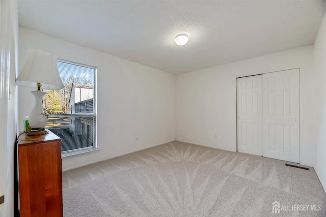 unfurnished bedroom with a closet, carpet floors, and a textured ceiling