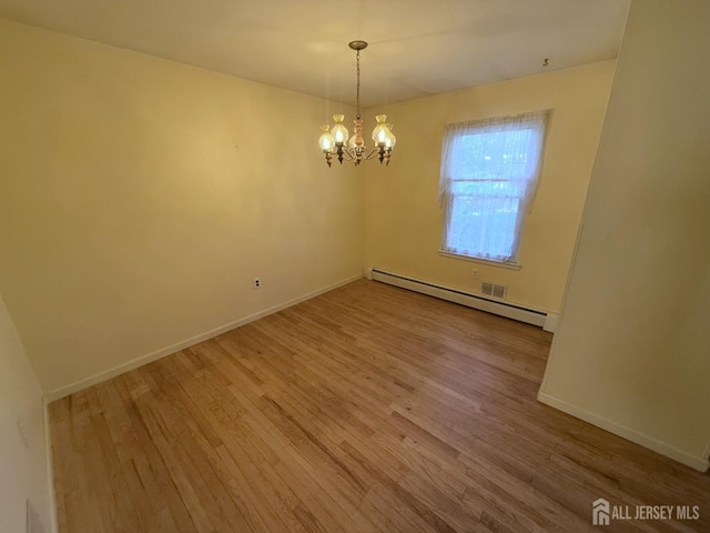 empty room featuring hardwood / wood-style flooring, a baseboard radiator, and a notable chandelier