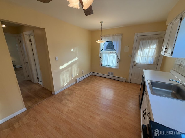 unfurnished dining area with light hardwood / wood-style floors, sink, a baseboard heating unit, and ceiling fan