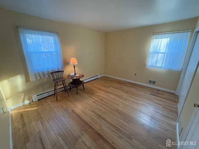 unfurnished room featuring a baseboard radiator and light wood-type flooring