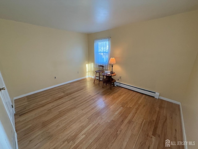 unfurnished room featuring baseboard heating and light wood-type flooring