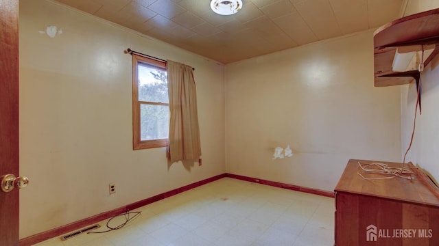 empty room with crown molding, light floors, visible vents, and baseboards