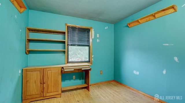 empty room featuring light wood finished floors and baseboards