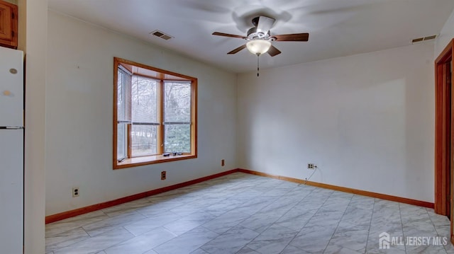 spare room with marble finish floor, baseboards, visible vents, and ceiling fan