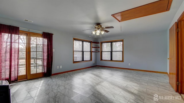 unfurnished room featuring attic access, visible vents, ceiling fan, and baseboards