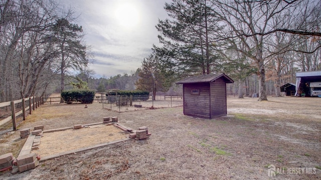 view of yard with an outdoor structure, a shed, and fence