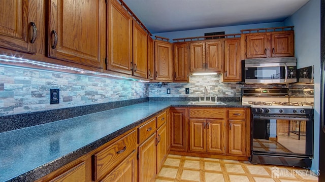 kitchen featuring stainless steel microwave, brown cabinets, a sink, and gas stove