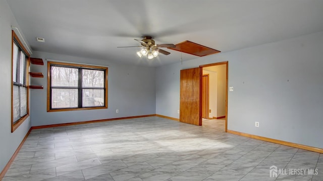 empty room with attic access, baseboards, and a ceiling fan