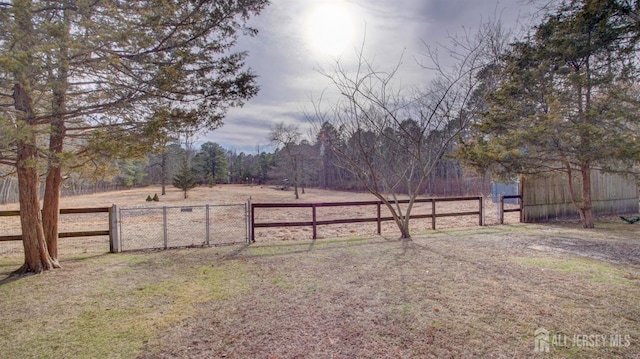 view of yard featuring a gate, a rural view, and fence