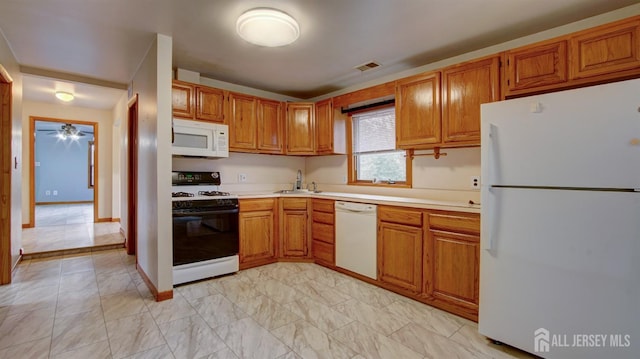 kitchen with white appliances, a sink, visible vents, light countertops, and brown cabinetry