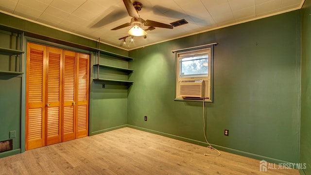 unfurnished bedroom featuring baseboards, ornamental molding, wood finished floors, cooling unit, and a closet