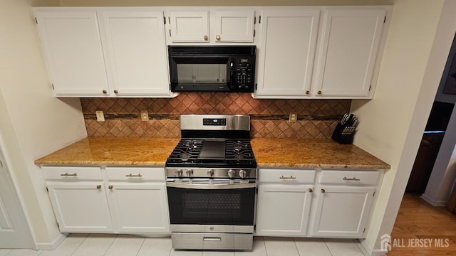 kitchen featuring light stone counters, white cabinets, and stainless steel range with gas stovetop