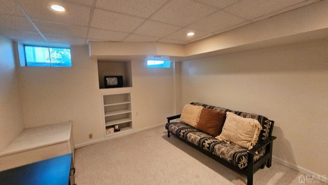 living area with carpet flooring, built in features, and a drop ceiling