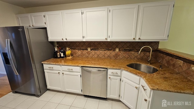 kitchen featuring white cabinets, stainless steel appliances, sink, light tile patterned floors, and stone counters