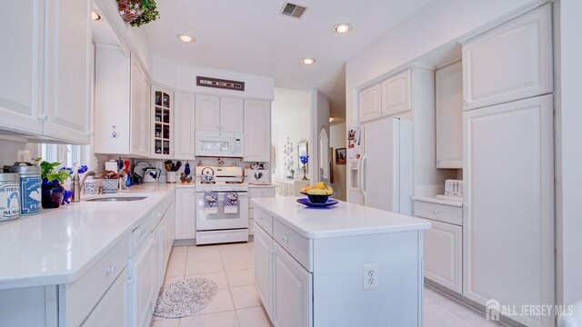 kitchen featuring sink, white appliances, a center island, and white cabinets