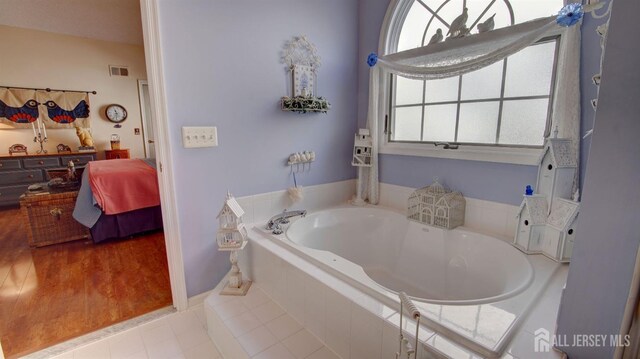 bathroom with tile patterned flooring and tiled tub