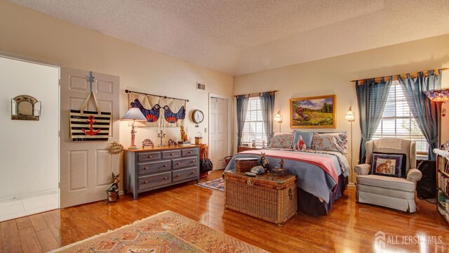 bedroom with a textured ceiling and light hardwood / wood-style flooring