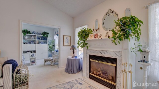 sitting room with a textured ceiling, carpet flooring, a fireplace, and vaulted ceiling