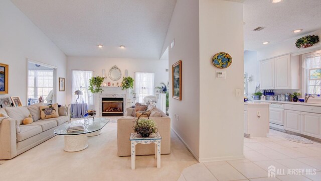 tiled living room featuring sink, a premium fireplace, a textured ceiling, and a wealth of natural light