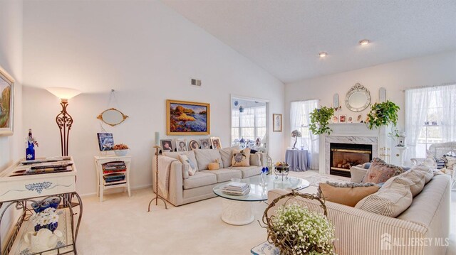 living room featuring light colored carpet, high vaulted ceiling, and a high end fireplace