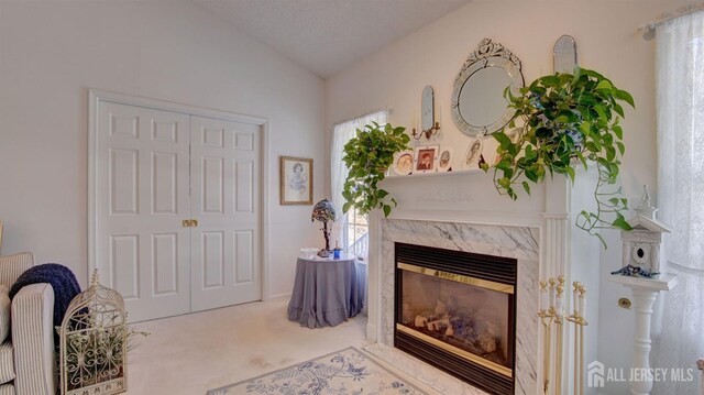 sitting room with a textured ceiling, lofted ceiling, carpet flooring, and a fireplace