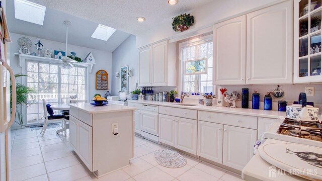 kitchen featuring a skylight, dishwasher, white cabinetry, and light tile patterned flooring