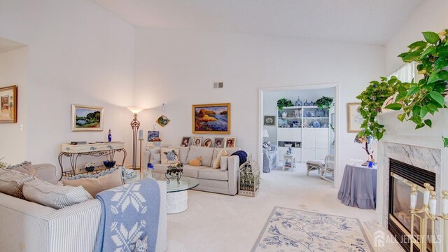 living room featuring a high end fireplace, high vaulted ceiling, and light carpet