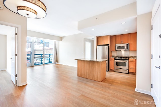 20 Livingston Ave Unit 504, New Brunswick, NJ 08901 - kitchen featuring appliances with stainless steel finishes, light wood-type flooring, a center island, brown cabinetry, and recessed lighting