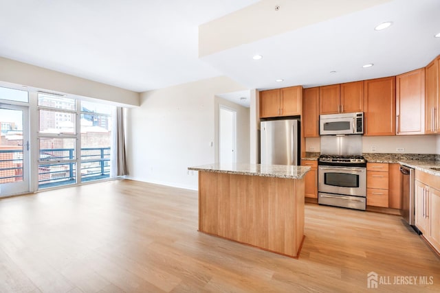 20 Livingston Ave Unit 504, New Brunswick, NJ 08901 - kitchen featuring appliances with stainless steel finishes, light wood-style flooring, light stone countertops, a center island, and recessed lighting