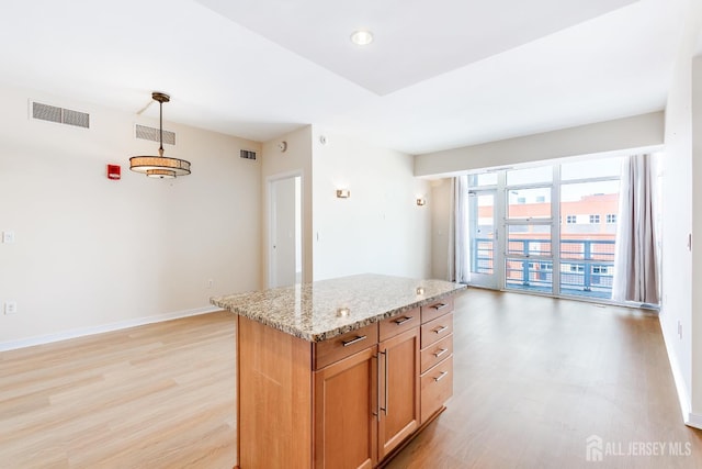20 Livingston Ave Unit 504, New Brunswick, NJ 08901 - kitchen featuring light wood-style floors, light stone countertops, hanging light fixtures, and a kitchen island