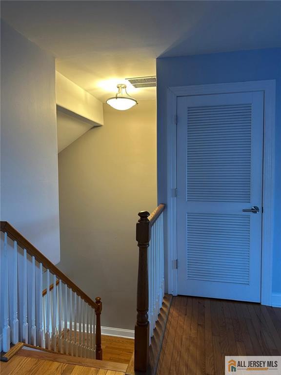 staircase with baseboards, visible vents, and wood finished floors
