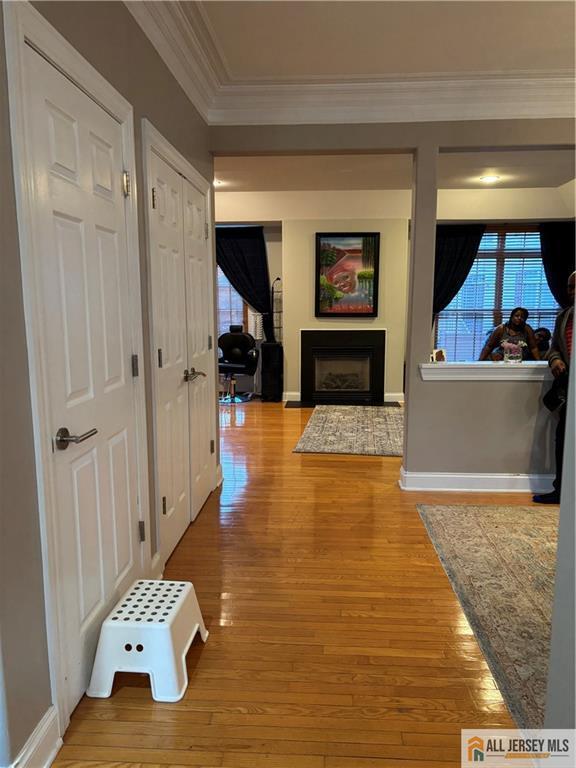 hall with crown molding, light wood finished floors, and baseboards