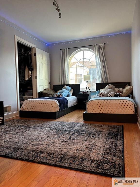 bedroom featuring rail lighting and wood-type flooring
