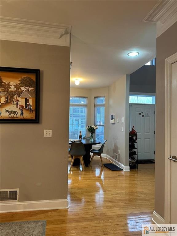 hallway with ornamental molding, visible vents, and baseboards