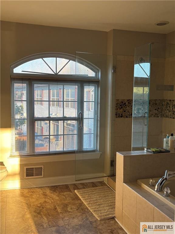 bathroom featuring tile patterned flooring, baseboards, visible vents, a stall shower, and a garden tub