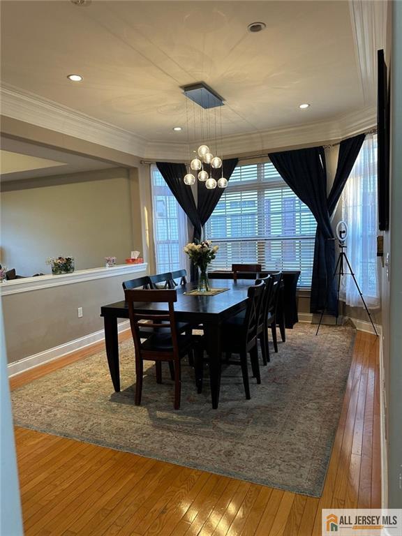 dining space with recessed lighting, ornamental molding, wood-type flooring, baseboards, and a notable chandelier
