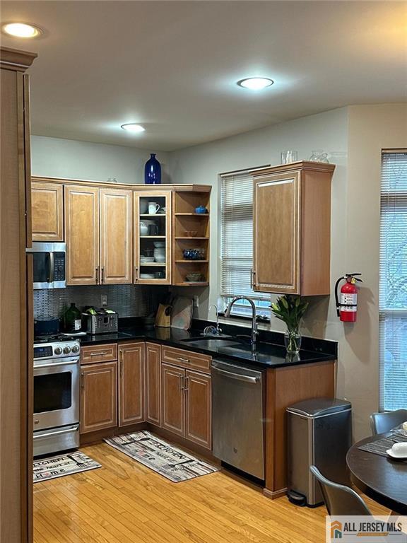kitchen with dark countertops, stainless steel appliances, light wood-style flooring, and a sink