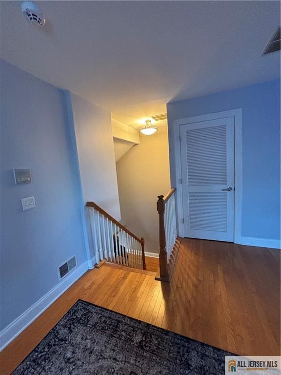stairs with wood finished floors, visible vents, and baseboards