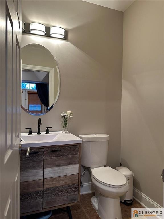 half bathroom featuring tile patterned floors, vanity, toilet, and baseboards