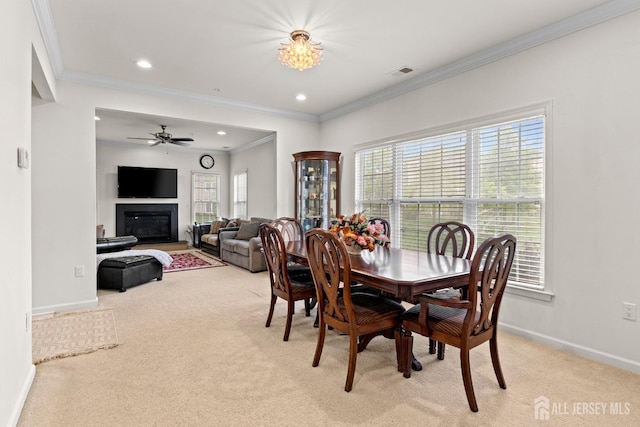 dining area featuring light colored carpet, ornamental molding, plenty of natural light, baseboards, and ceiling fan