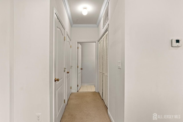 hallway featuring light carpet, crown molding, and baseboards