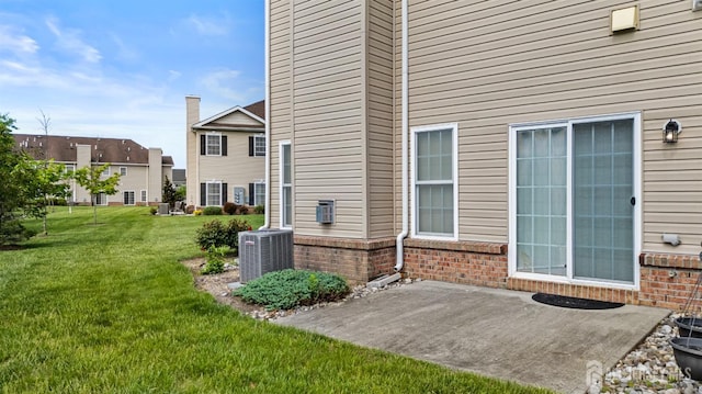 rear view of property featuring a patio, brick siding, central AC unit, and a lawn