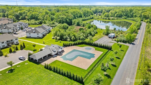aerial view of residential area featuring a large body of water and a heavily wooded area