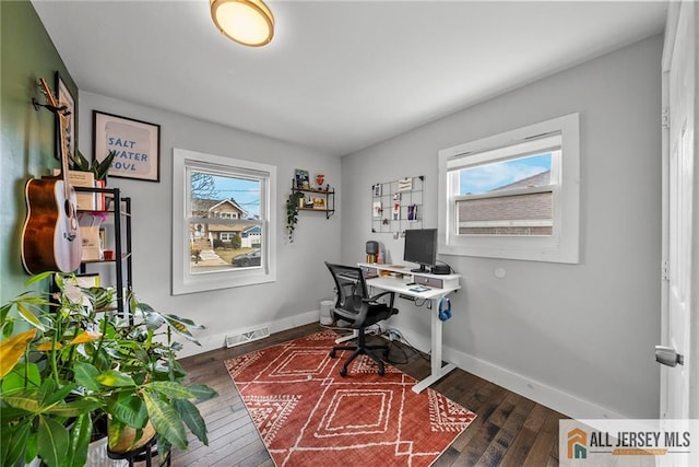 office featuring baseboards, dark wood finished floors, visible vents, and a healthy amount of sunlight